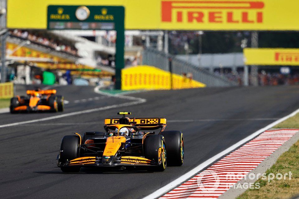 Lando Norris, McLaren MCL38, passes Oscar Piastri, McLaren MCL38, as he exits the pit lane