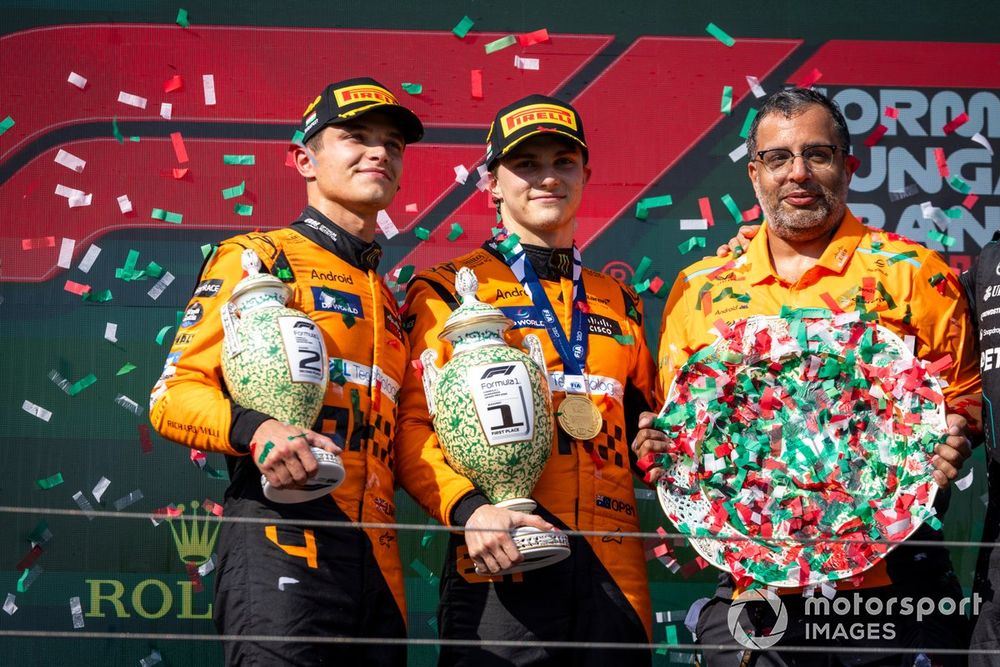 Lando Norris, McLaren F1 Team, 2nd position, Oscar Piastri, McLaren F1 Team, 1st position, and the McLaren trophy delegate with the trophies on the podium