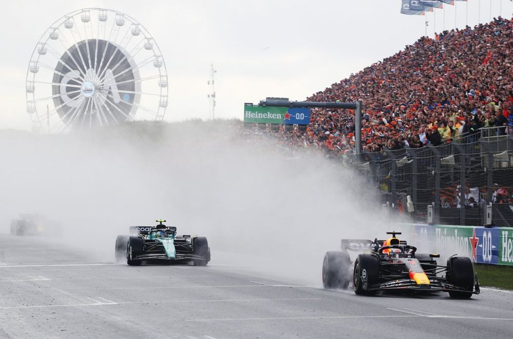 Max Verstappen, Red Bull Racing, ahead of an Aston Martin at a wet Dutch GP, 2023.