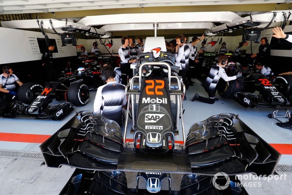 A nose cone in front of the McLaren garage. Jenson Button and Fernando Alonso wait in their McLaren MP4-31 Honda cars